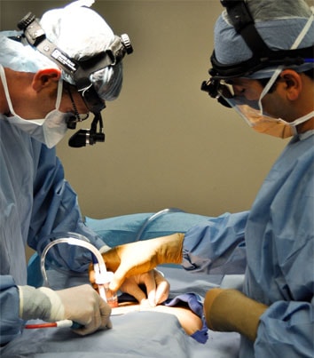 Cirujanos extrayendo grasa a un paciente durante una intervención de liposucción en Valencia.